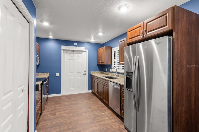 kitchen featuring light stone countertops, dark hardwood / wood-style flooring, a textured ceiling, stainless steel appliances, and sink