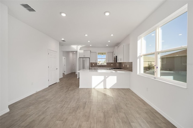 kitchen with kitchen peninsula, white cabinetry, light wood-type flooring, and appliances with stainless steel finishes