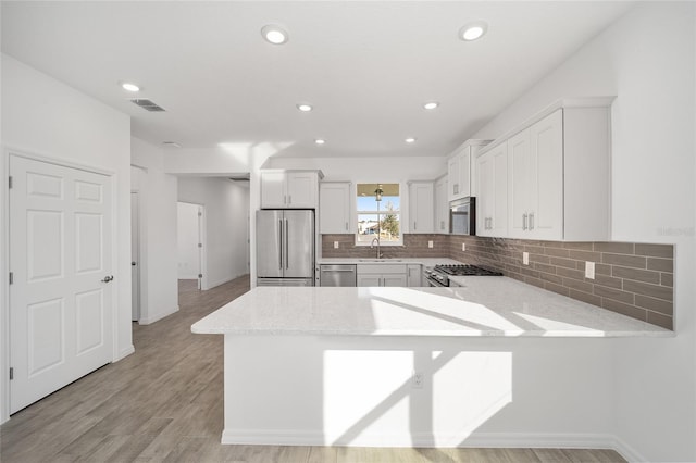 kitchen with kitchen peninsula, stainless steel appliances, white cabinetry, and sink