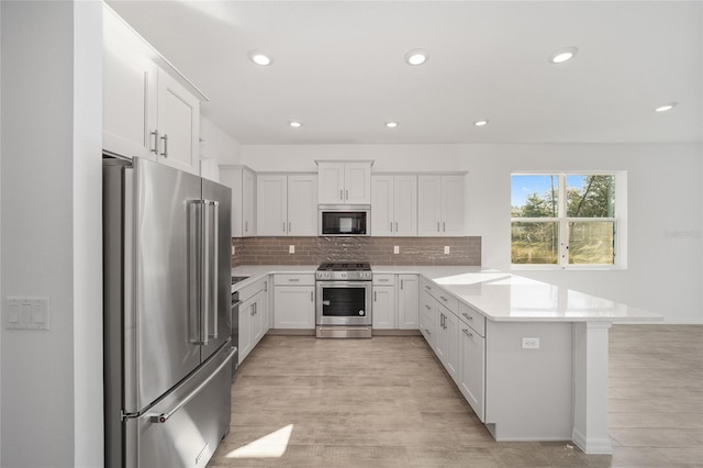 kitchen featuring tasteful backsplash, light hardwood / wood-style flooring, white cabinets, and stainless steel appliances