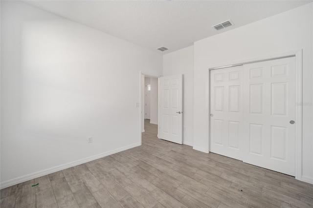 unfurnished bedroom with a closet and light hardwood / wood-style flooring