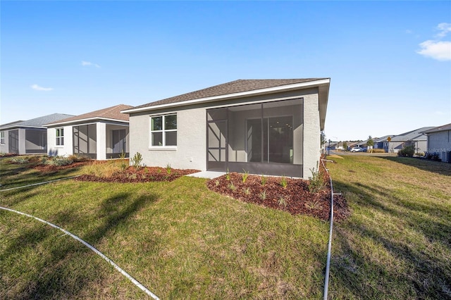 rear view of house with a lawn and a sunroom