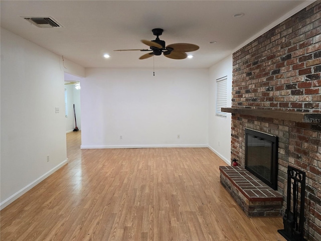 unfurnished living room featuring ceiling fan, light wood-type flooring, and a brick fireplace