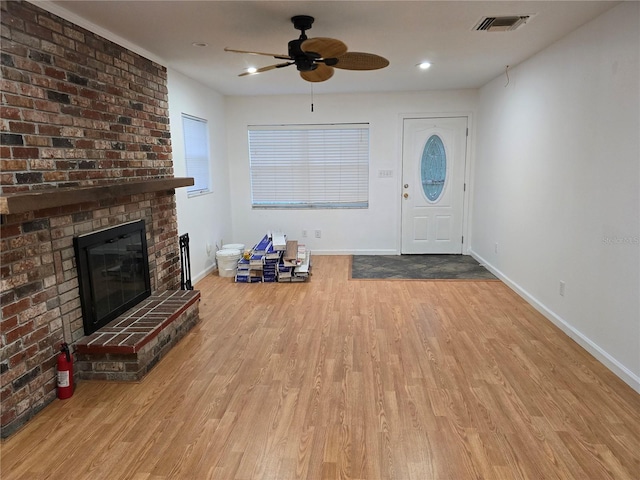 foyer with ceiling fan, light hardwood / wood-style floors, and a brick fireplace