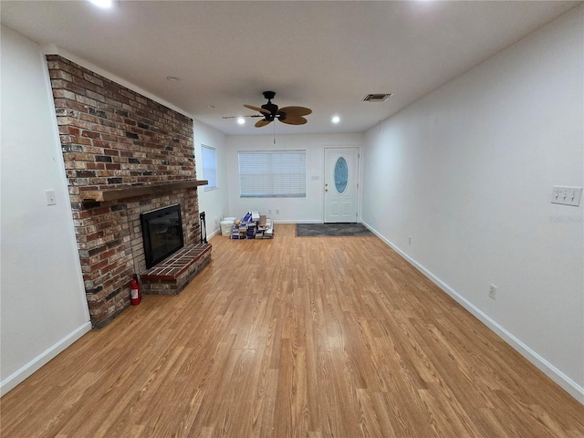 unfurnished living room with light hardwood / wood-style floors, a brick fireplace, and ceiling fan