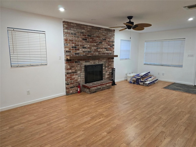 unfurnished living room with a brick fireplace, light hardwood / wood-style flooring, and ceiling fan