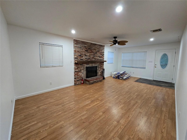 unfurnished living room featuring a fireplace, light hardwood / wood-style flooring, and ceiling fan