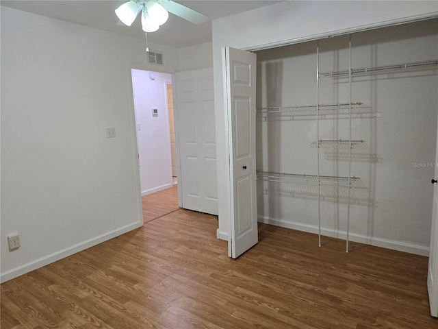 unfurnished bedroom with ceiling fan, a closet, and hardwood / wood-style flooring