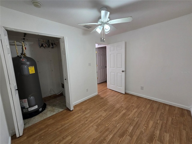 interior space with electric water heater, hardwood / wood-style flooring, and ceiling fan