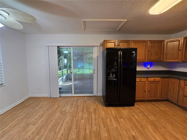 kitchen with black fridge, ceiling fan, a textured ceiling, and light wood-type flooring