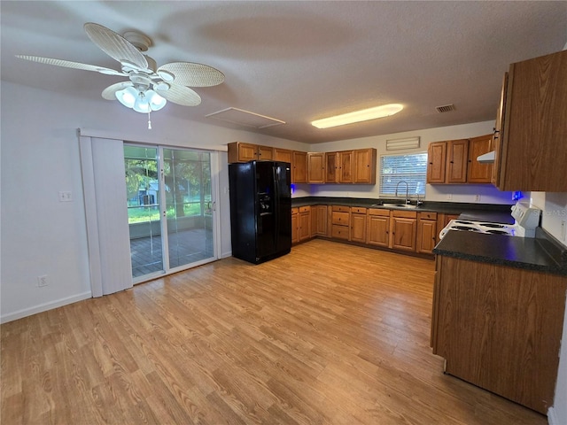 kitchen featuring range with electric cooktop, black fridge with ice dispenser, sink, and a wealth of natural light