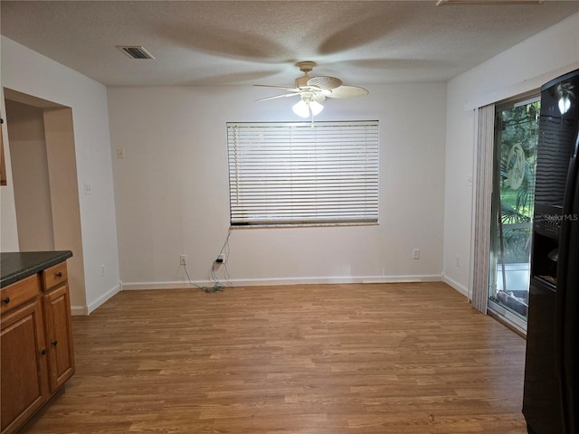 unfurnished dining area featuring ceiling fan, light hardwood / wood-style floors, and a textured ceiling