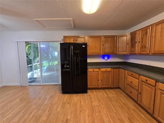 kitchen with a textured ceiling, light wood-type flooring, and black fridge