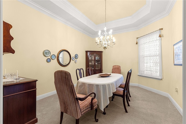 carpeted dining room featuring a tray ceiling, ornamental molding, and a notable chandelier