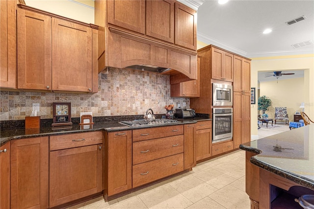 kitchen with decorative backsplash, stainless steel appliances, ceiling fan, and dark stone counters