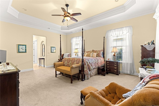 bedroom featuring a raised ceiling, ceiling fan, crown molding, and light carpet