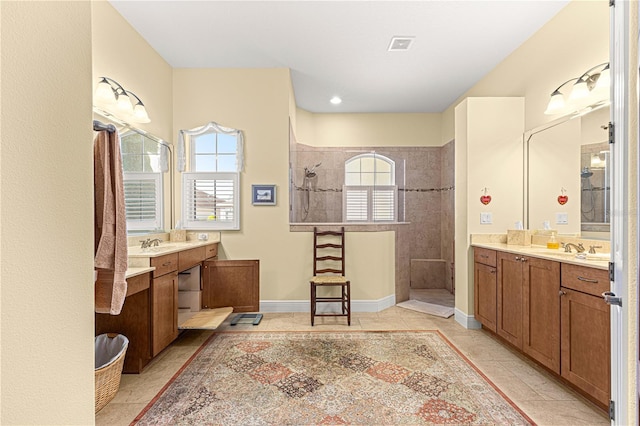 bathroom featuring a tile shower, tile patterned flooring, and vanity