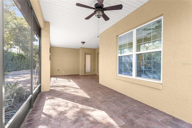 unfurnished sunroom with ceiling fan and plenty of natural light