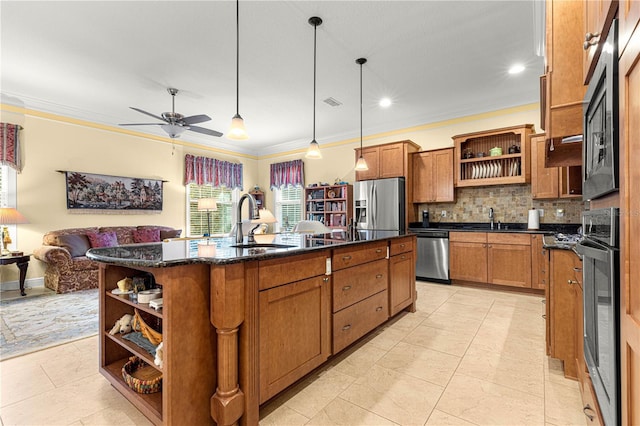 kitchen featuring pendant lighting, sink, decorative backsplash, an island with sink, and appliances with stainless steel finishes