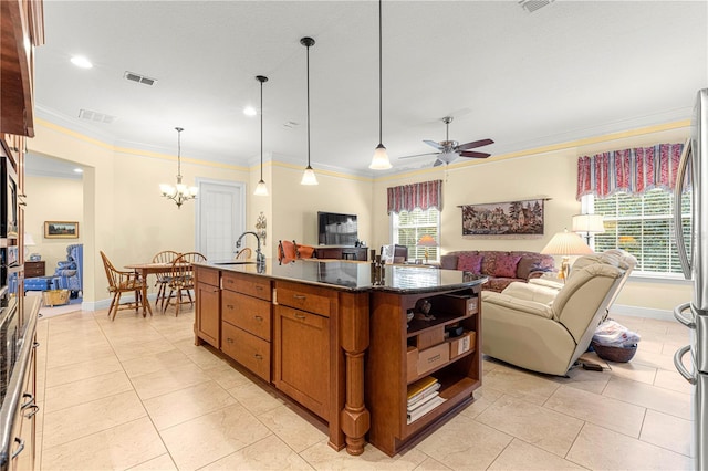 kitchen with ornamental molding, ceiling fan with notable chandelier, a healthy amount of sunlight, a center island with sink, and hanging light fixtures