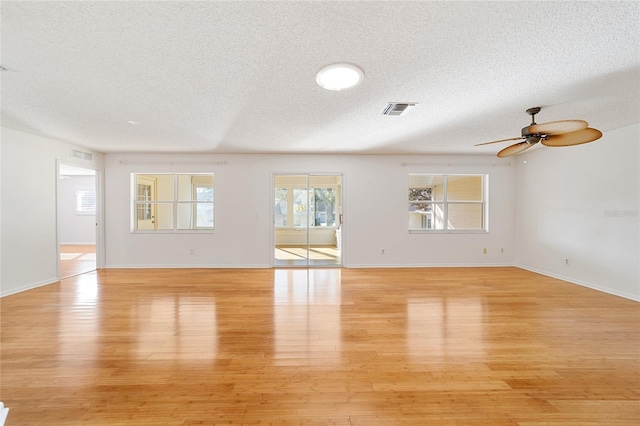 spare room featuring a textured ceiling, light wood-type flooring, and ceiling fan