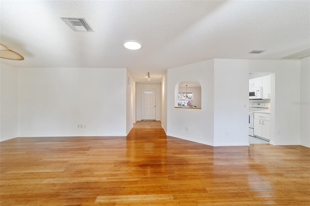 spare room with a textured ceiling and light wood-type flooring