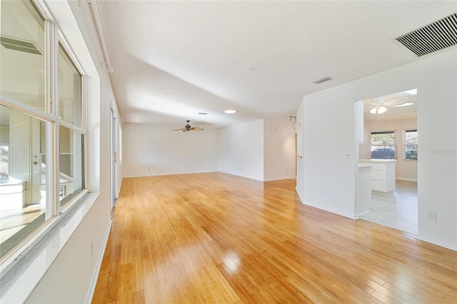 empty room featuring ceiling fan, light wood-type flooring, and a textured ceiling