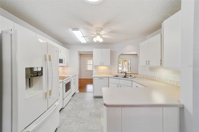 kitchen featuring kitchen peninsula, sink, white cabinets, and white appliances