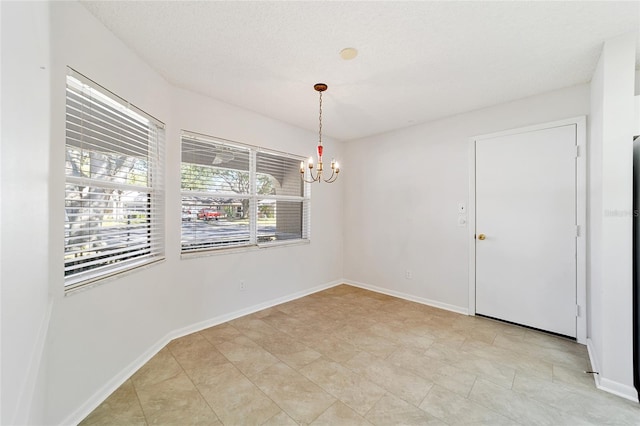 spare room with a wealth of natural light, a textured ceiling, and a notable chandelier