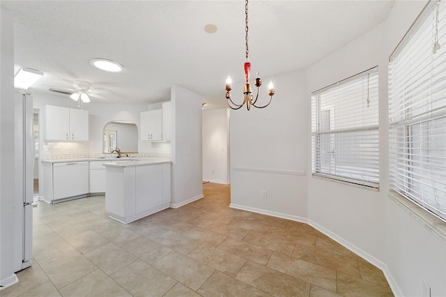 kitchen featuring kitchen peninsula, tasteful backsplash, ceiling fan with notable chandelier, white appliances, and hanging light fixtures