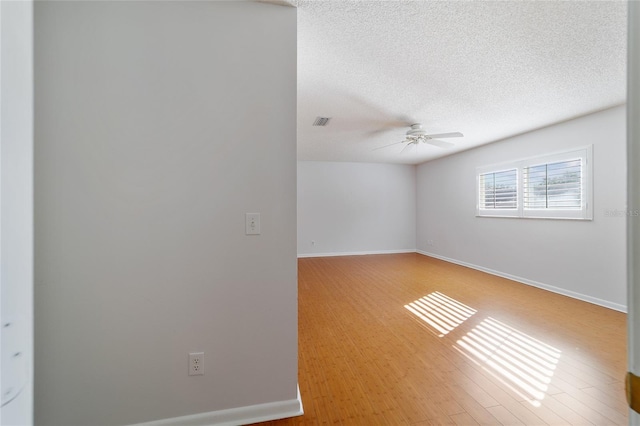 spare room featuring ceiling fan, light wood-type flooring, and a textured ceiling