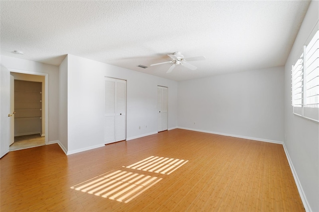 empty room with ceiling fan, wood-type flooring, and a textured ceiling