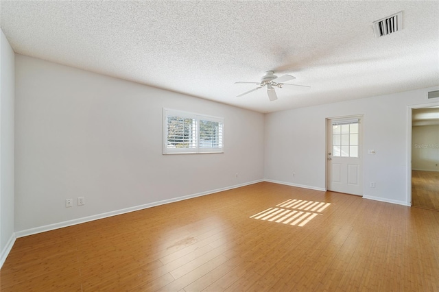 spare room featuring ceiling fan, light hardwood / wood-style flooring, and a textured ceiling