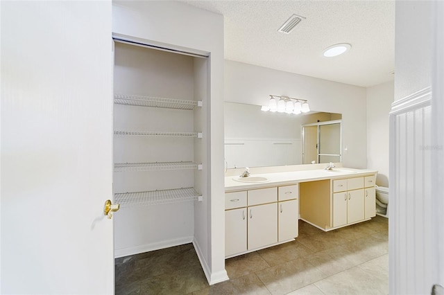 bathroom with tile patterned floors, vanity, a textured ceiling, and toilet