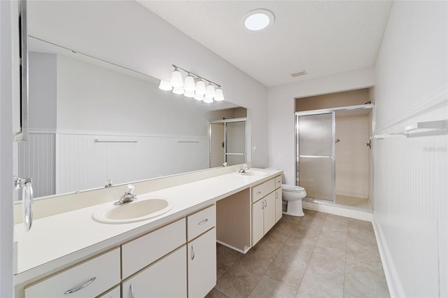 bathroom with a textured ceiling, vanity, toilet, and a shower with shower door