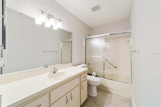 full bathroom featuring tile patterned flooring, bath / shower combo with glass door, a textured ceiling, toilet, and vanity