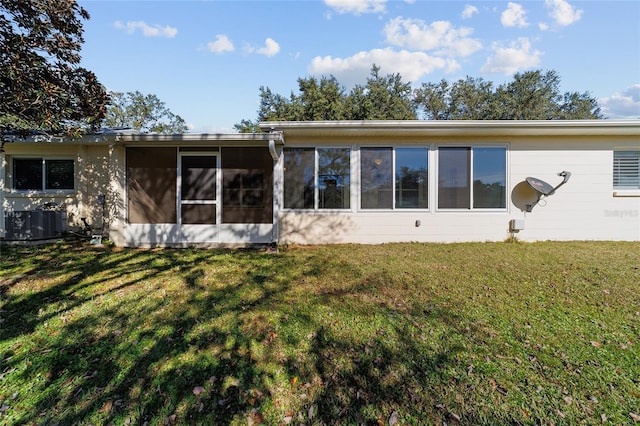 rear view of house featuring a yard, a sunroom, and central air condition unit