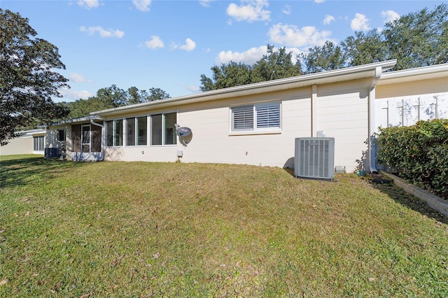 back of house featuring a sunroom, a yard, and central AC