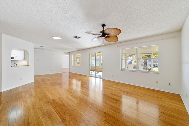 unfurnished living room with a textured ceiling, light hardwood / wood-style flooring, and ceiling fan