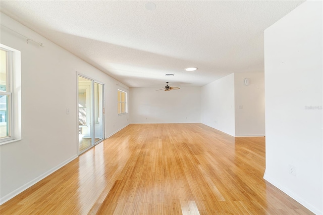 empty room with ceiling fan, light hardwood / wood-style floors, and a textured ceiling