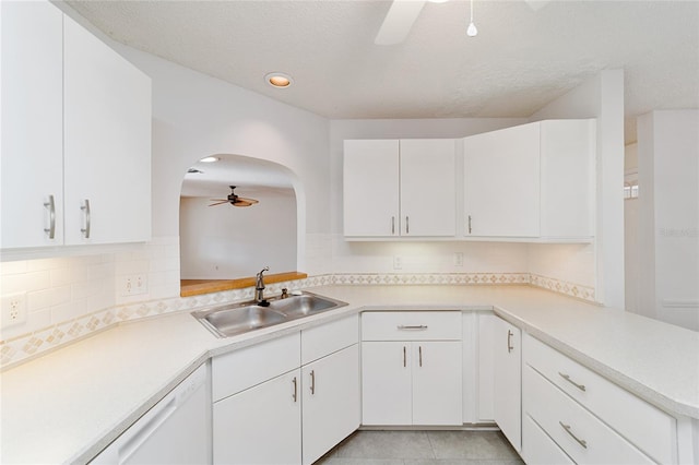 kitchen with kitchen peninsula, white dishwasher, ceiling fan, sink, and white cabinets