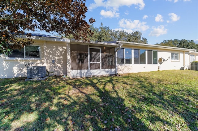 back of property with central air condition unit, a sunroom, and a yard