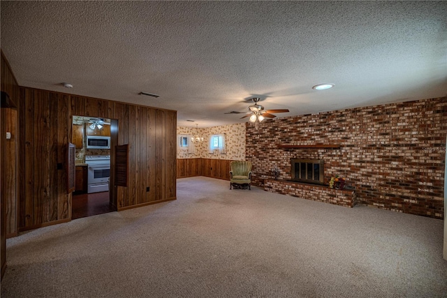 unfurnished living room with a fireplace, carpet, a textured ceiling, and wood walls