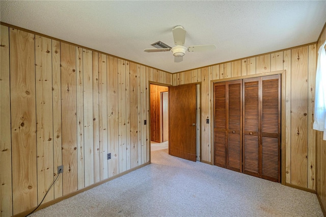 unfurnished bedroom featuring a textured ceiling, a closet, light colored carpet, and ceiling fan