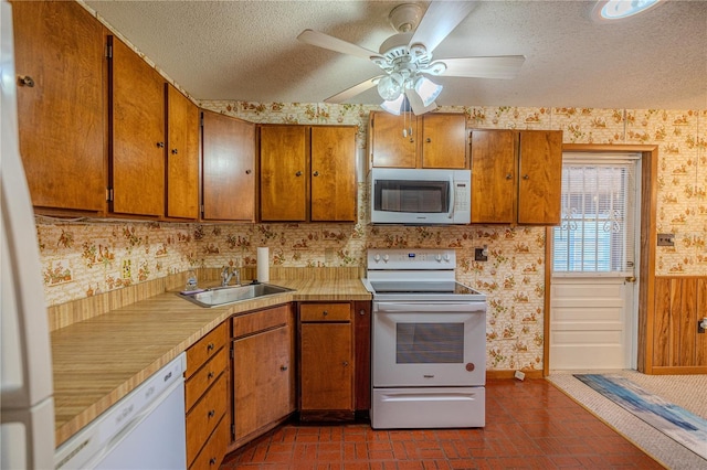 kitchen with a textured ceiling, ceiling fan, white appliances, and sink