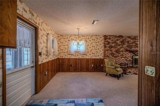 sitting room with a textured ceiling, carpet floors, an inviting chandelier, and wood walls