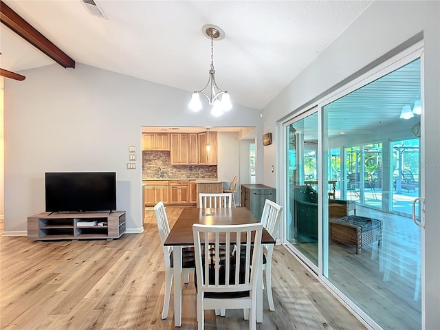 dining space with a notable chandelier, lofted ceiling with beams, and light hardwood / wood-style flooring