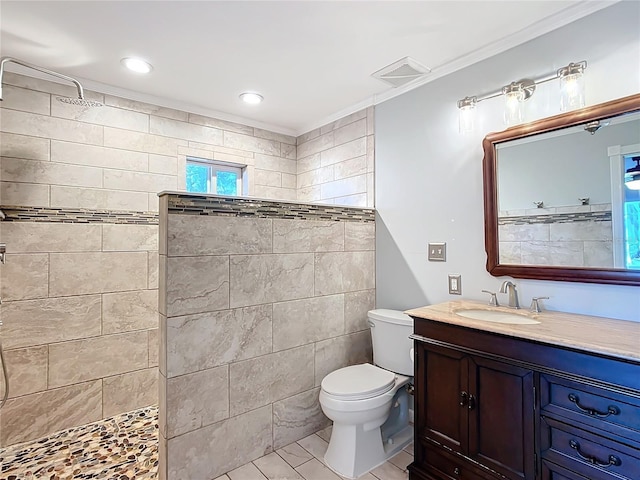 bathroom featuring a tile shower, vanity, toilet, and crown molding