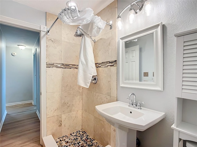 bathroom with hardwood / wood-style flooring, sink, and tiled shower