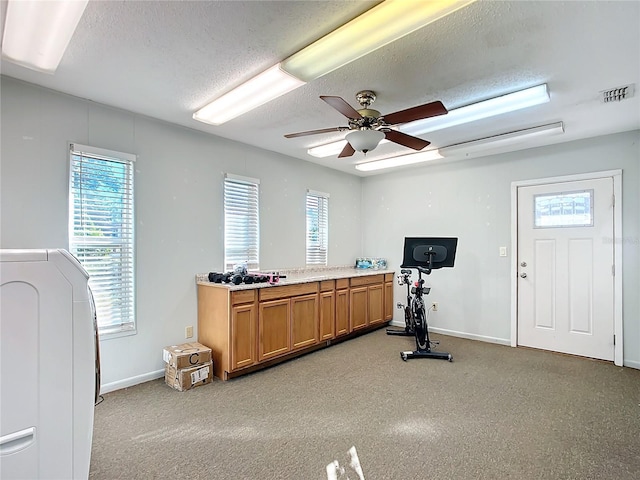 exercise area featuring ceiling fan and a textured ceiling